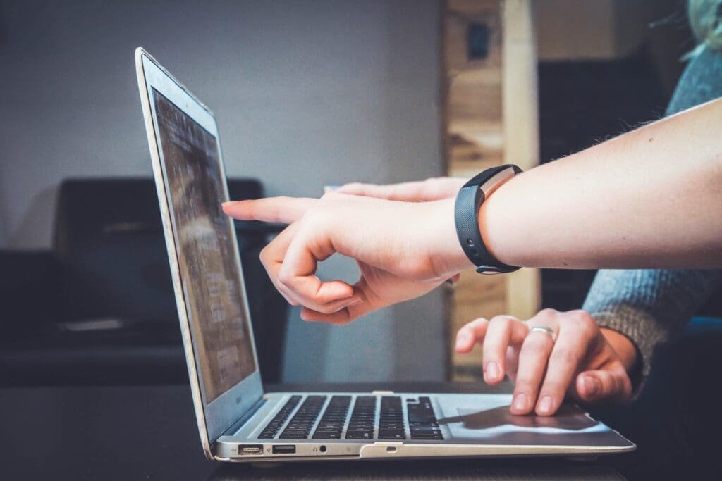 Two hands interact with a laptop