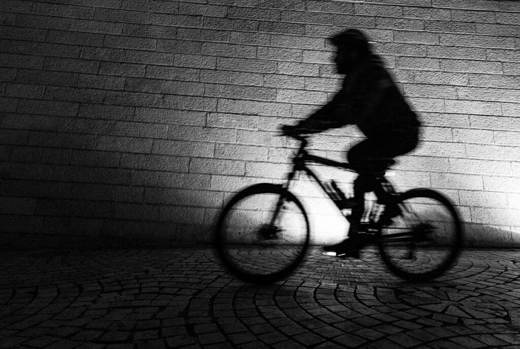 A cyclist rides along a cobblestone path