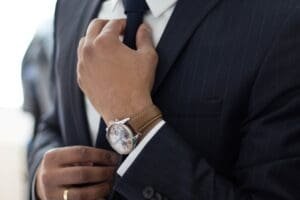 A man in a pinstriped suit adjusts his tie
