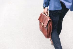 Man in a blue suit walking with a brown leather briefcase