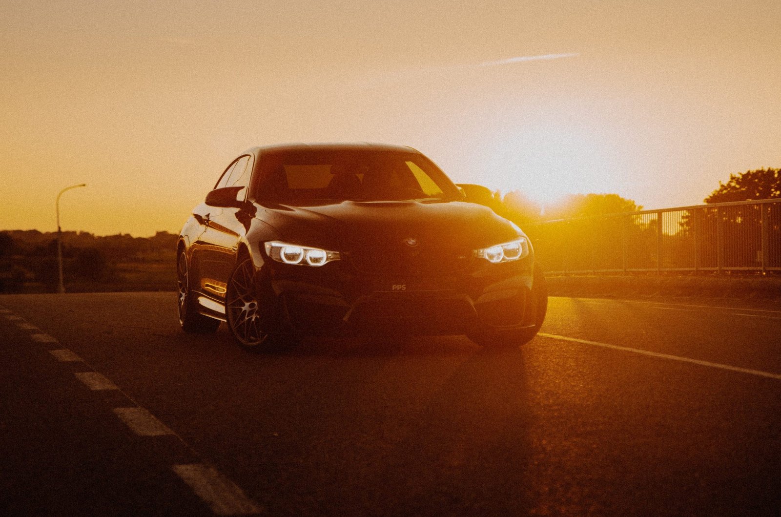 A sleek black BMW parked on the road at sunset