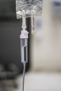 IV drip setup featuring a clear plastic drip chamber and tubing, used for administering fluids in a medical setting.