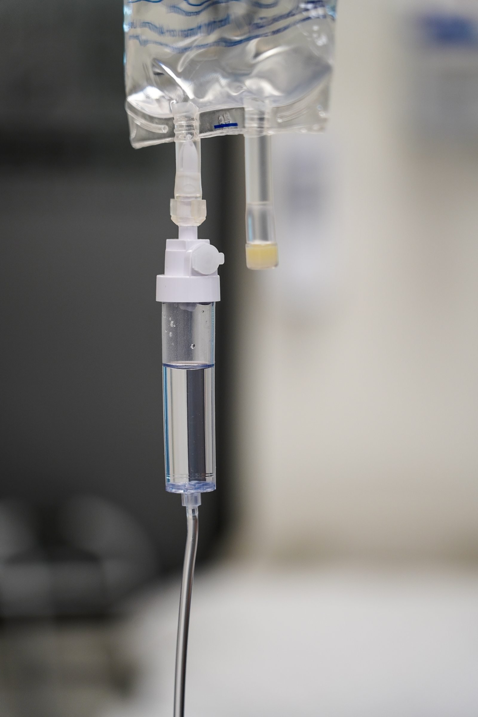 IV drip setup featuring a clear plastic drip chamber and tubing, used for administering fluids in a medical setting.