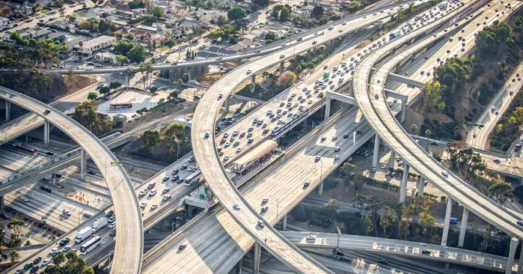 Aerial view of a busy highway interchange surrounded by urban development, showcasing multiple lanes of traffic and roadways intersecting.