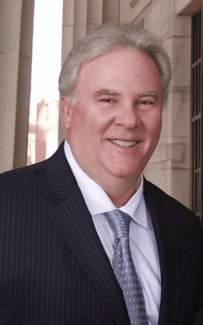 Attorney Sanford Kassel wearing a dark business suit, white shirt and silver-blue tie | in front of a courthouse