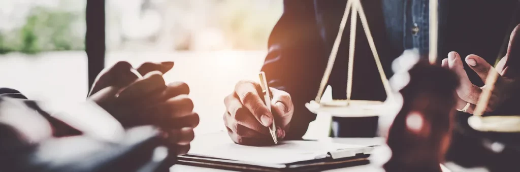 A lawyer writes notes while discussing legal matters with clients, highlighting the importance of communication in legal consultations.