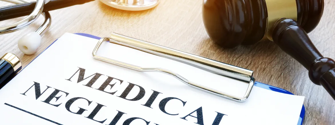 A legal gavel rests beside a clipboard featuring the words "MEDICAL NEGLIGENCE," symbolizing the intersection of healthcare and law.