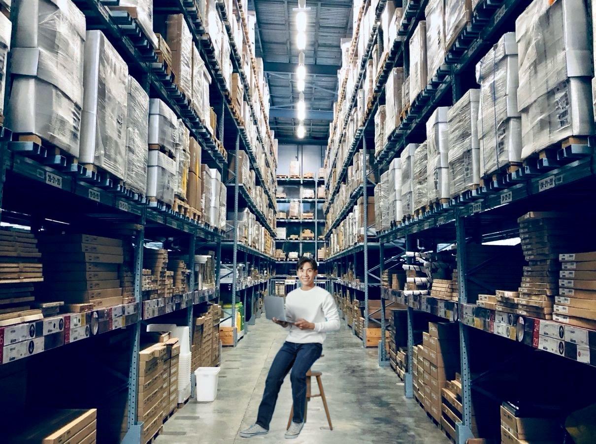 young man working in a warehouse sitting on a stool as the only seat he could find
