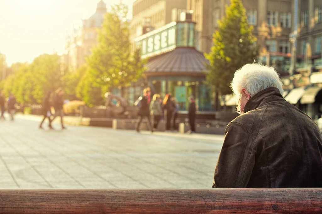 An elderly man sits on a bench